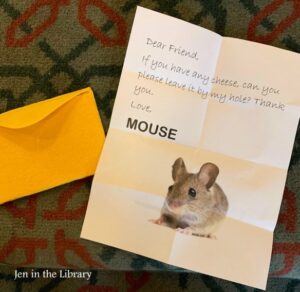 Photo of a typed letter reading: Dear Friend, If you have any cheese, can you please leave it by my hole? Thank you. Love, Mouse" with a photo of a mouse below the text. A yellow envelope is beside the letter, and a watermark reads Jen in the Library.